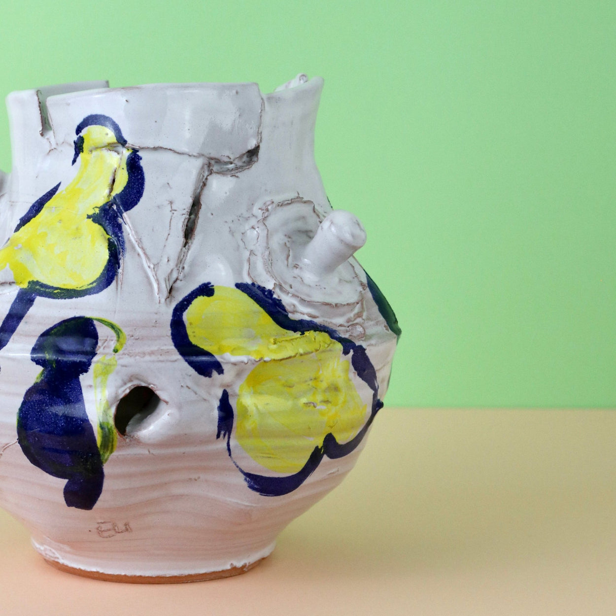 Modern Ceramic Vase by Elin Hughes against a light green and peach background. Close up.