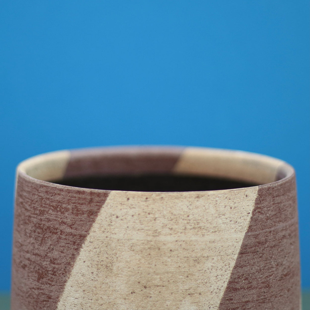Ceramic Stripe Bowl by Amanda-Sue Rope with blue green background. Rim close up.