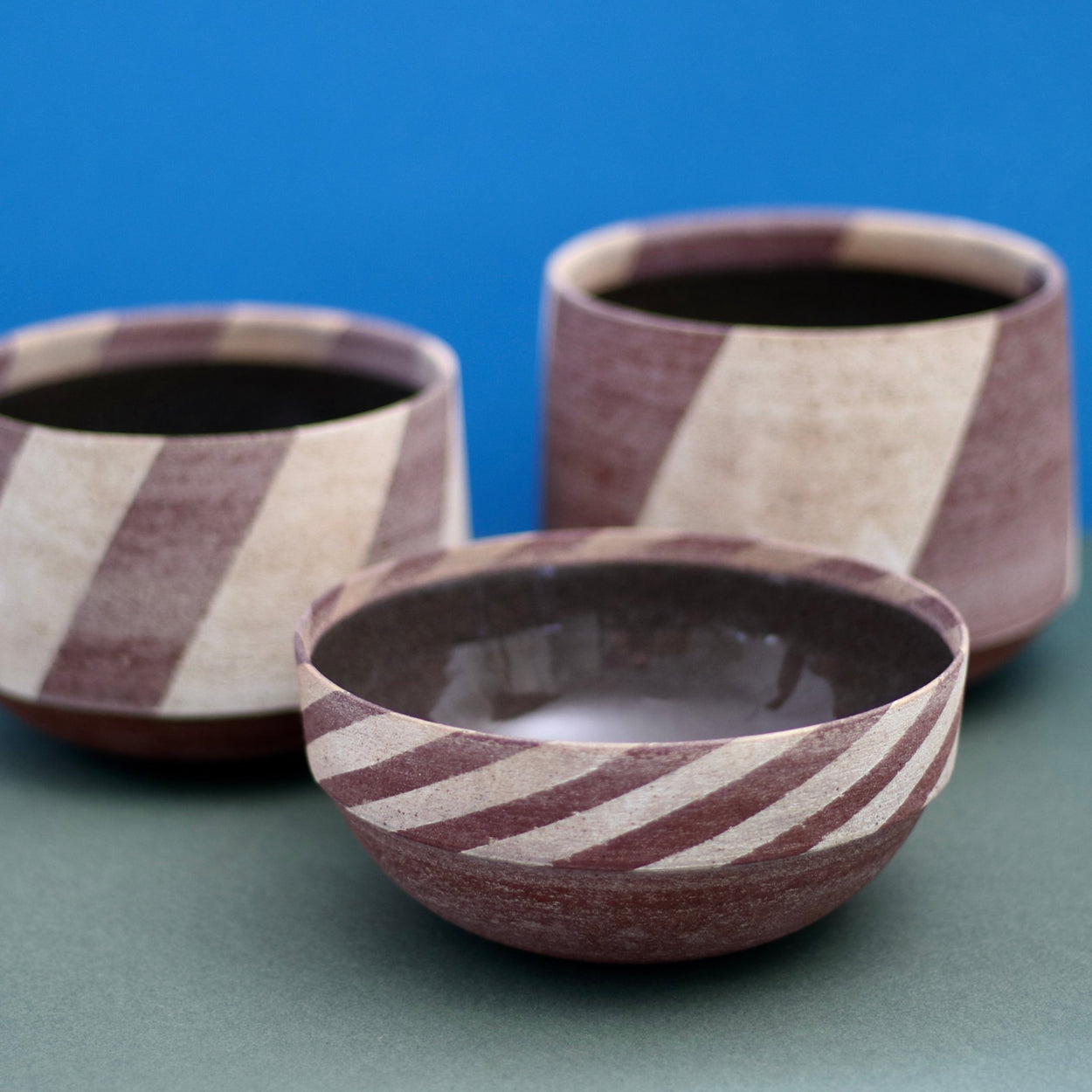 Ceramic Thin Stripe Bowl by Amanda-Sue Rope with blue green background. Group of three, close up on thin stripe bowl.