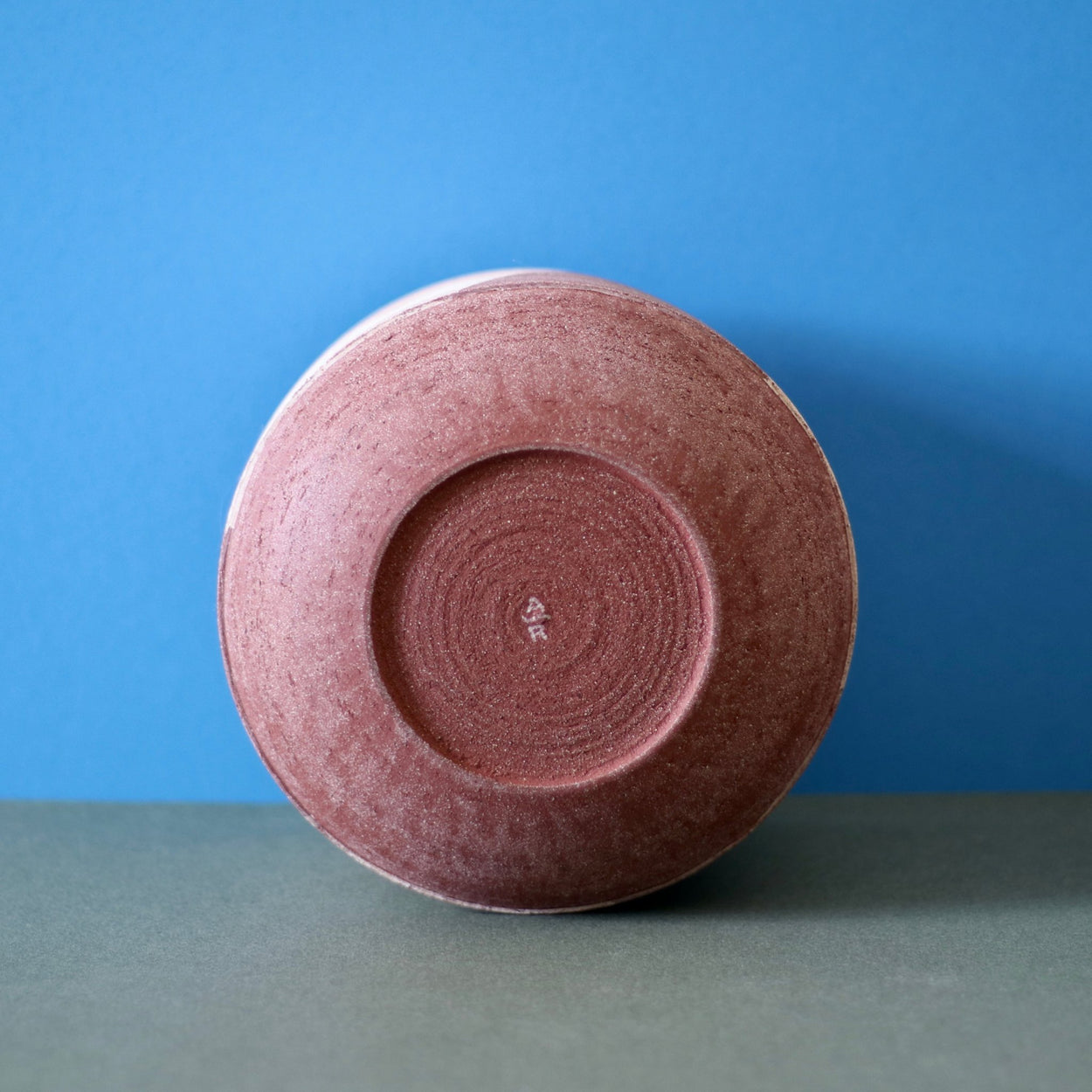 Ceramic Stripe Bowl by Amanda-Sue Rope with blue green background. Base with makers mark view.