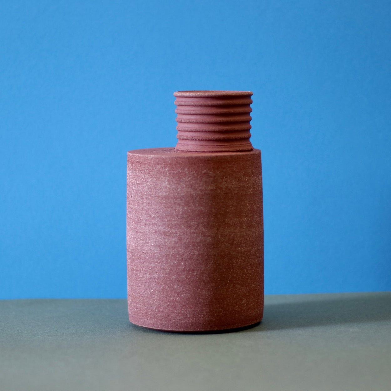 Handmade Ceramic Vase by Amanda-Sue Rope against a blue and green background.