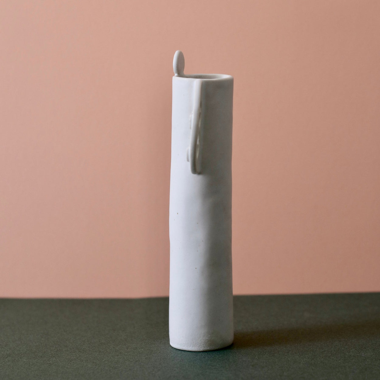 Cassie Hansen Tall Vase against green and peach background, side view.