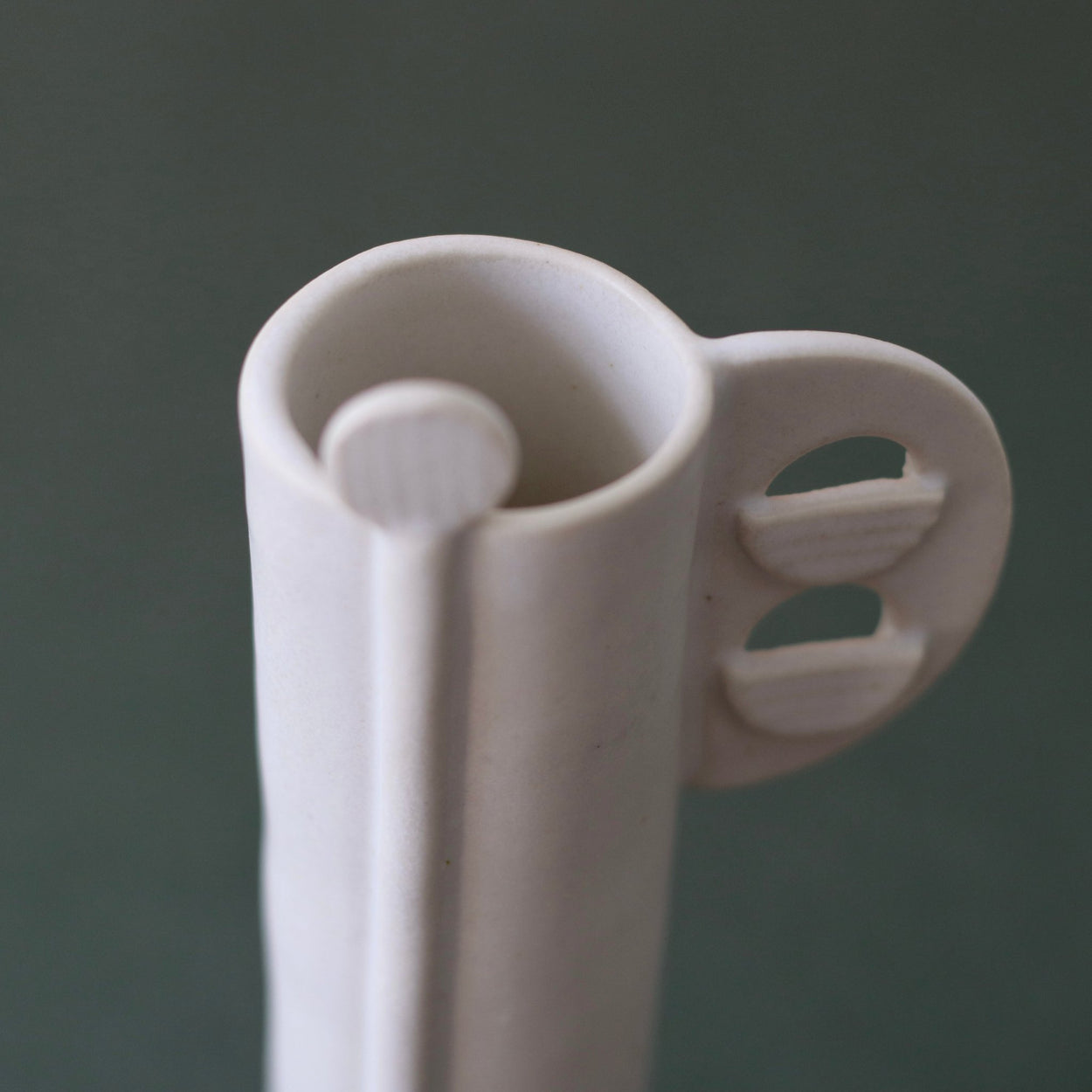 Cassie Hansen Tall Vase against green and peach background, close up view from above.