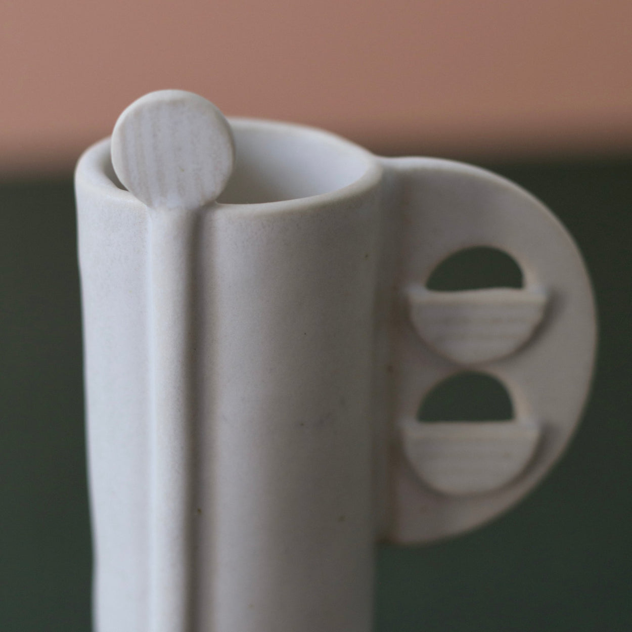 Cassie Hansen Tall Vase against green and peach background, close up view.