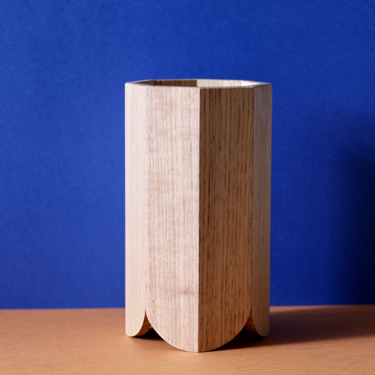 Handmade Wood Kitchen Utensil Holder in oak against a blue and brown background.