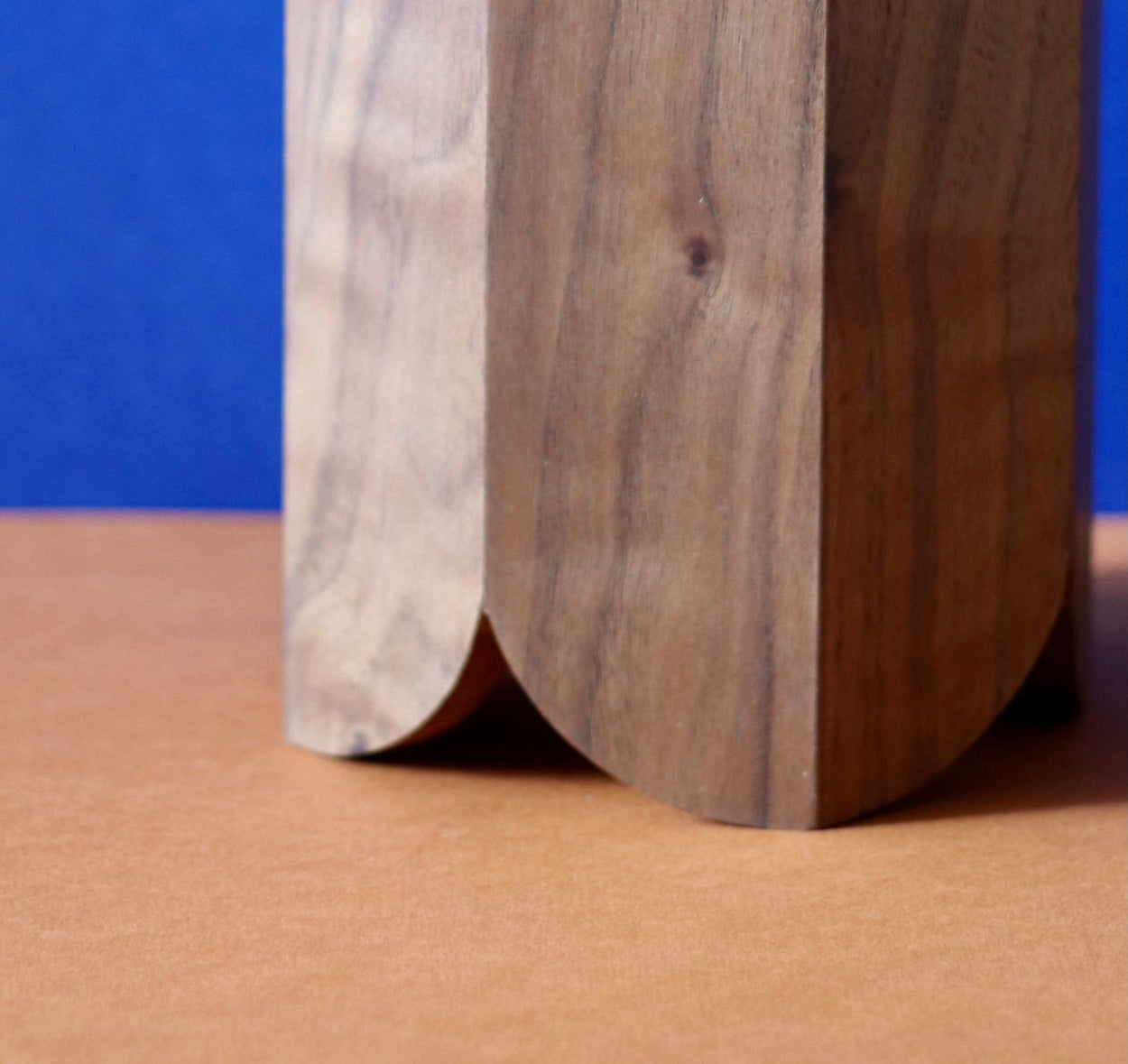 Close up of the Handmade Wood Kitchen Utensil Holder in walnut against a blue and brown background.