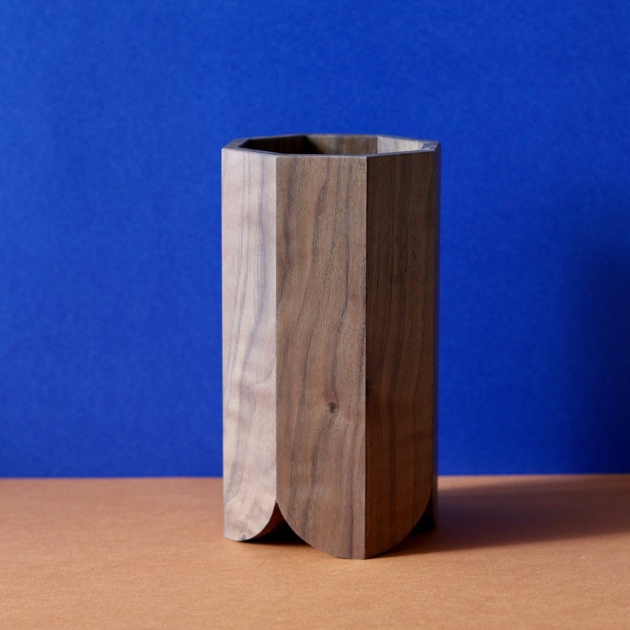 Handmade Wood Kitchen Utensil Holder in walnut against a blue and brown background.