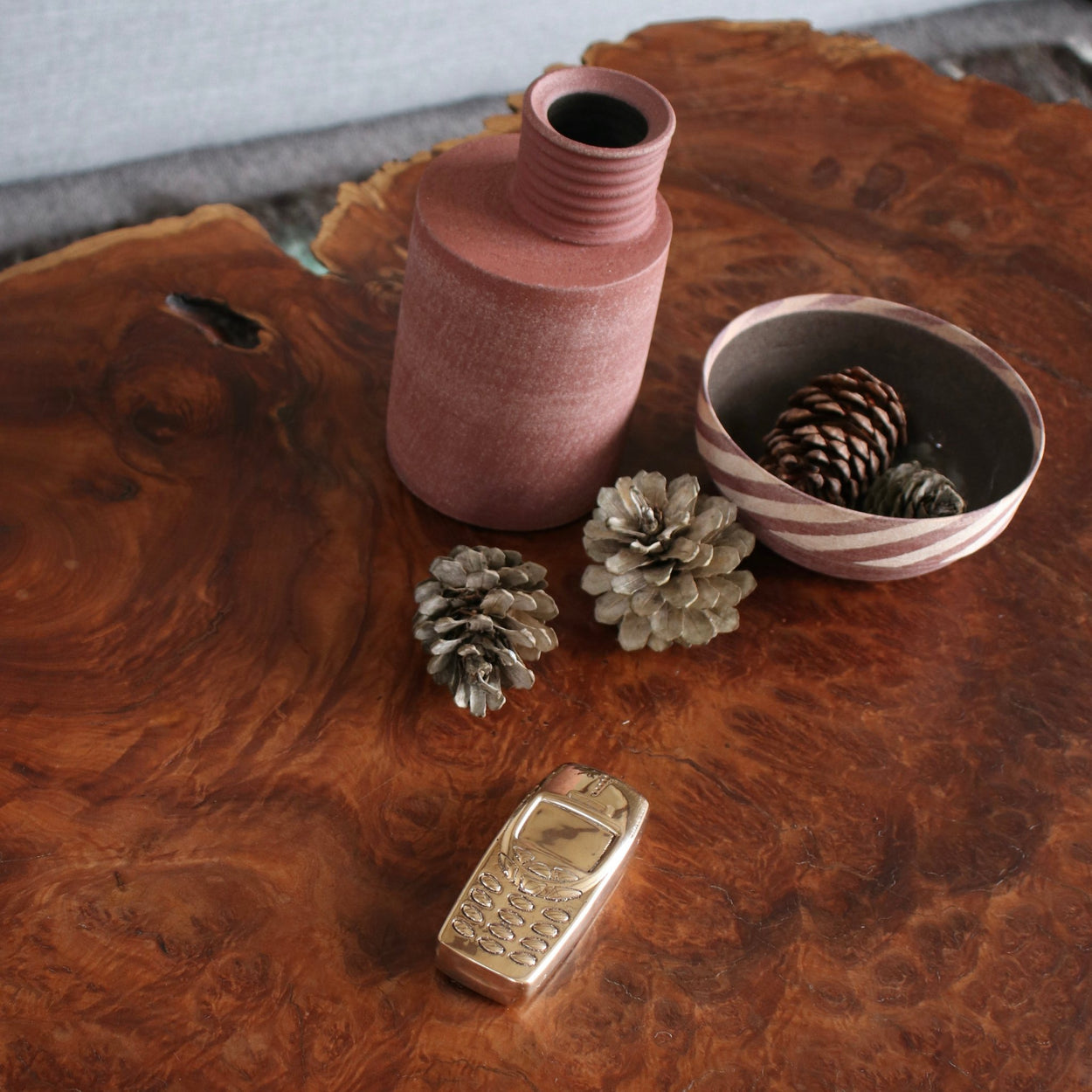 Bronze phone sculpture by Nancy Pearce sitting on a wood burl table.