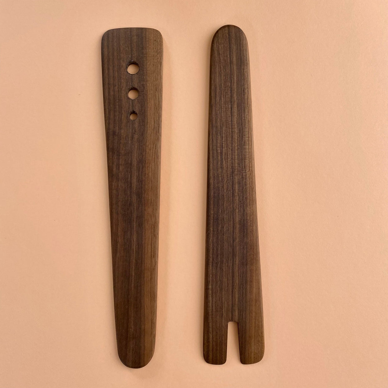Handmade Walnut Wood Salad Servers upright against a peach background. By Civil Dawn Studio.