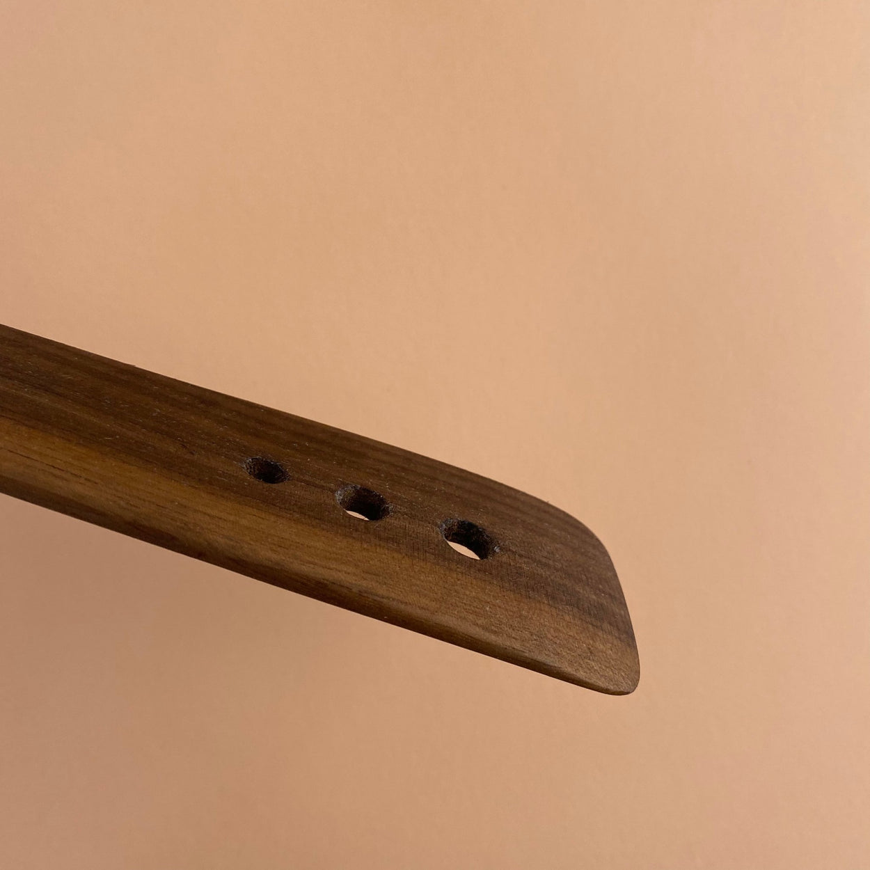 Side view of Handmade Walnut Wood Salad Servers upright against a peach background. By Civil Dawn Studio.