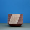 Striped ceramic bowl by Amanda Sue Rope against a blue and green background.