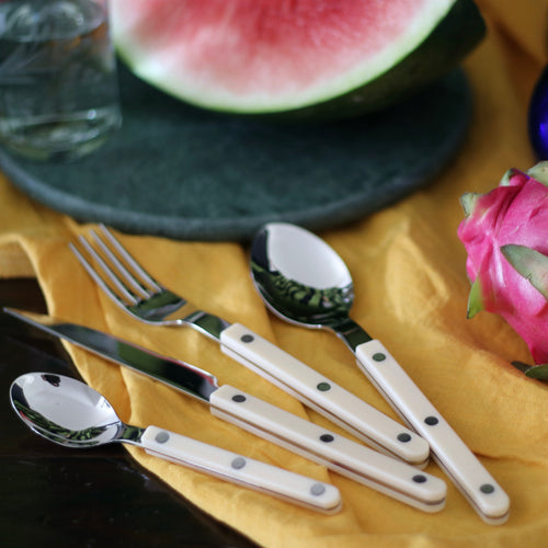 Ivory Sabre Paris cutlery set on yellow linen tablescape with tropical fruit and green marble plate