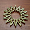 Futagami brass Galaxy Trivet against dark wooden table