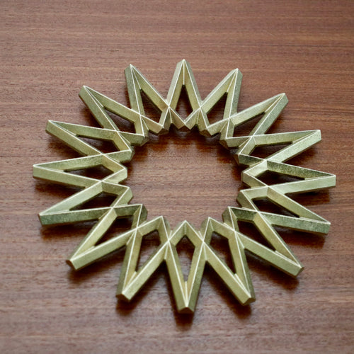 Futagami brass Galaxy Trivet against dark wooden table