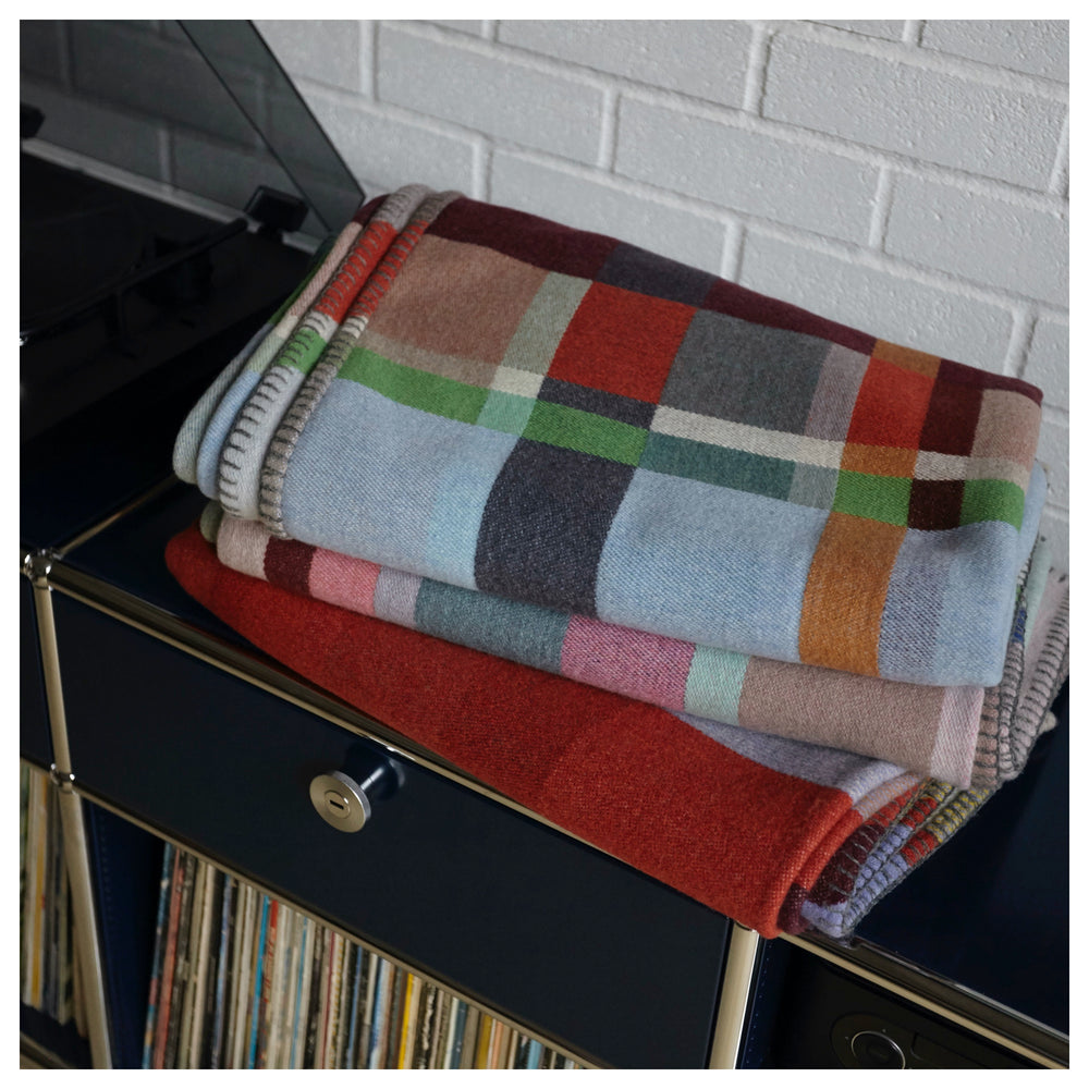 Two Wallace and Sewell colourful wool blankets folded on black buffet