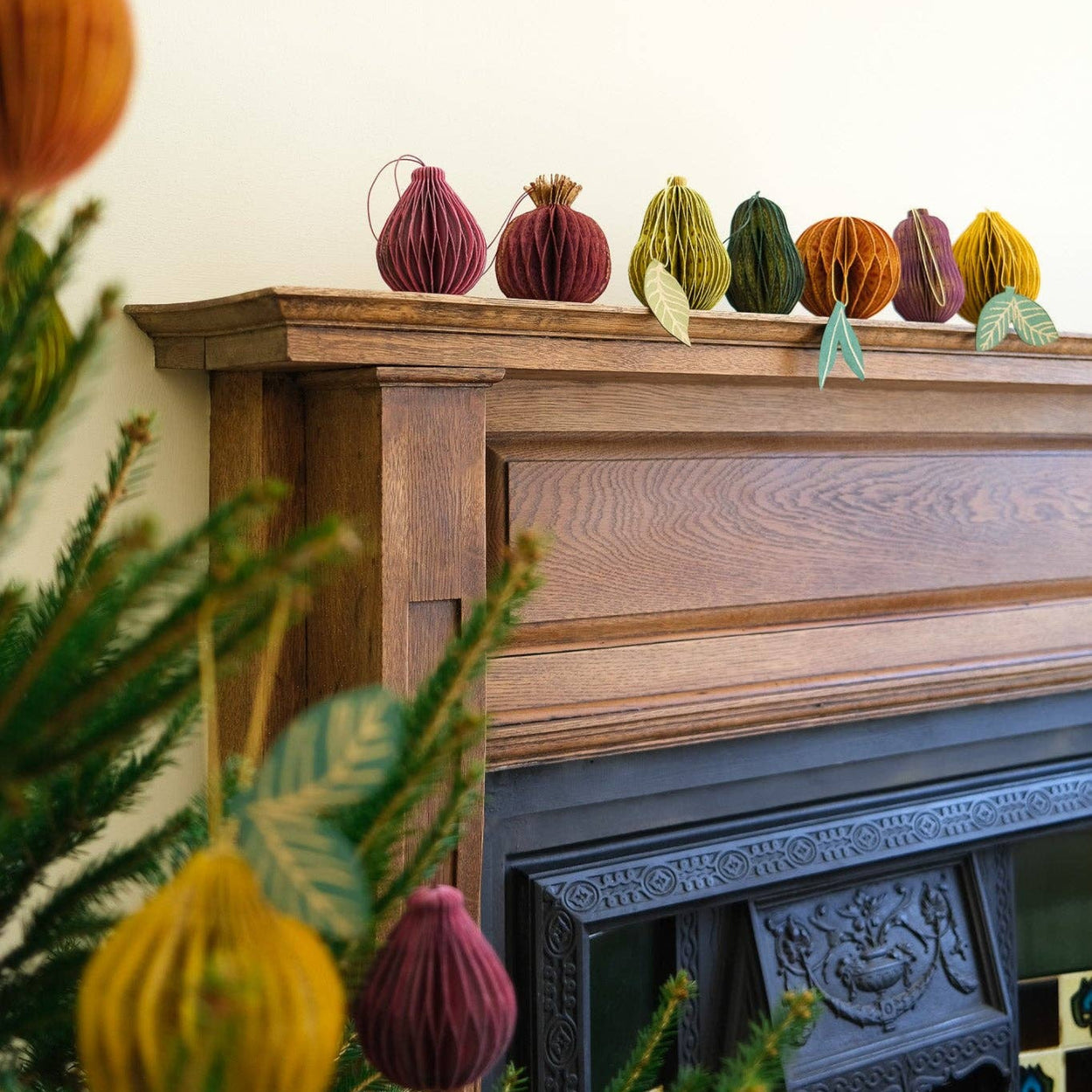 Decorative pumpkins on a mantelpiece with a Christmas tree in the foreground
