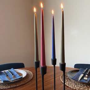 Candles on iron candlestick on wood table with place settings