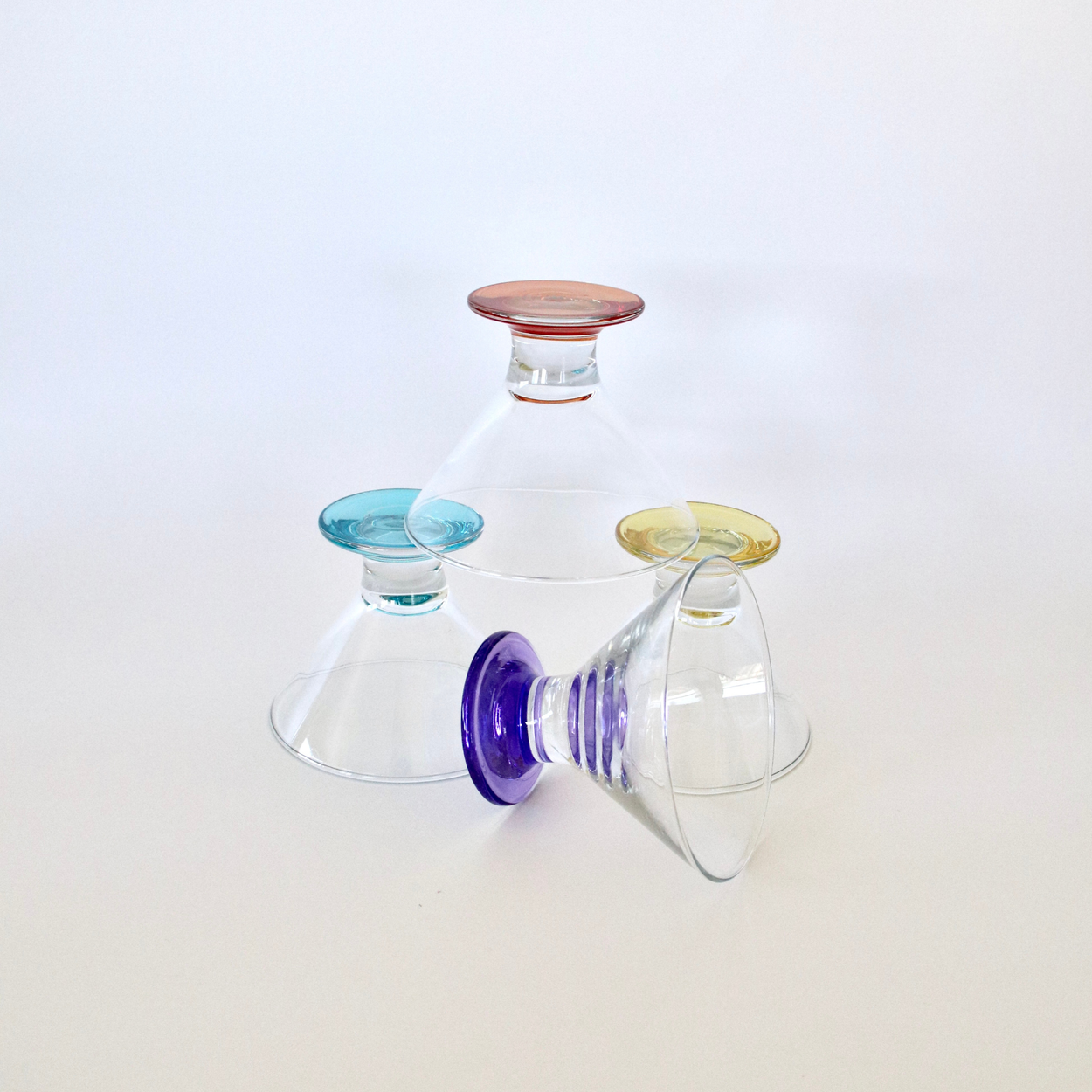 Set of three glass tumblers with colored bases on a white background