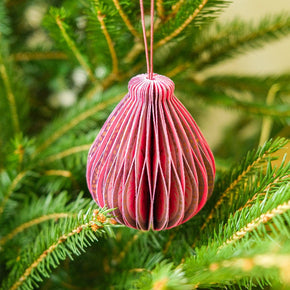 Pink paper ornament hanging on a green Christmas tree