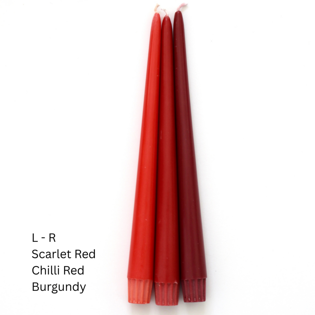 Three taper candles in red shades labeled Scarlet Red, Chilli Red, and Burgundy, standing vertically on a white background with text on the left.