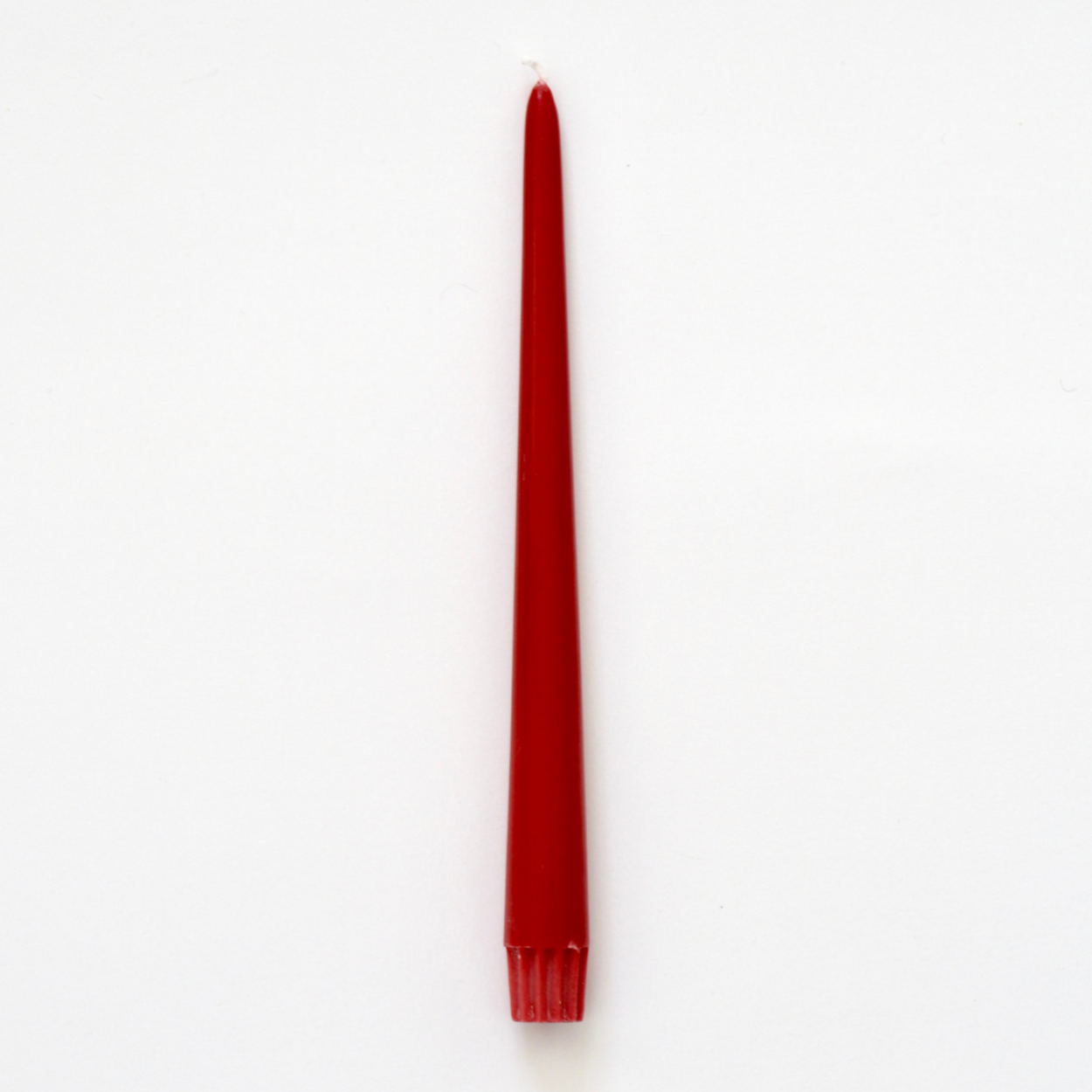 A single red taper candle standing vertically on a plain white background.