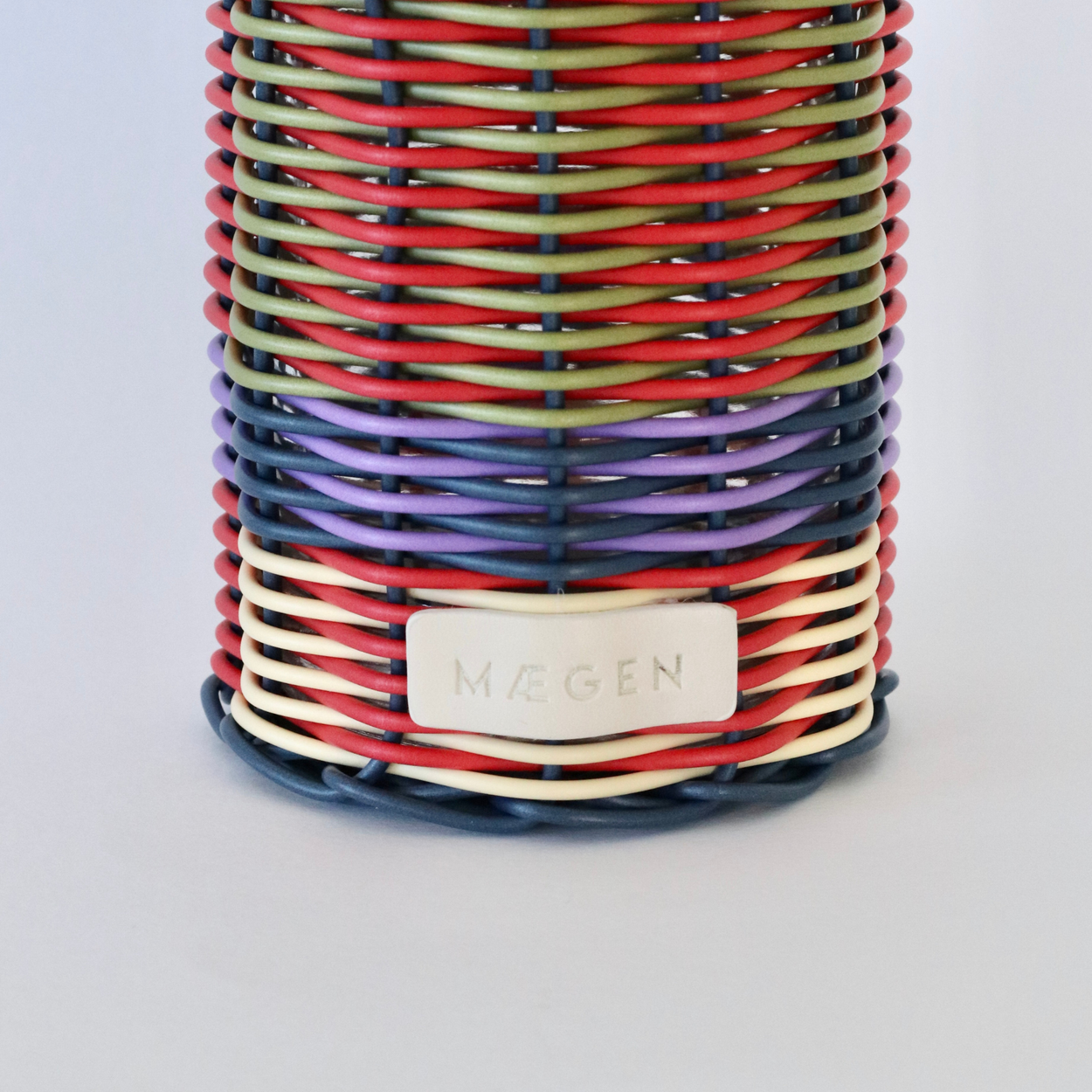 Decorative bottle with woven design and metallic nozzle on a white background