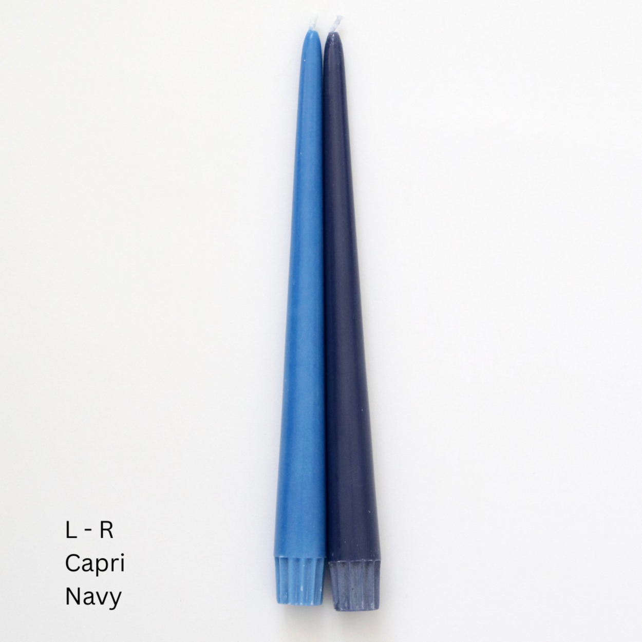 Two taper candles, one light blue labeled 'Capri' and one dark navy labeled 'Navy', standing upright on a plain white background with text indicating sizes and color names.