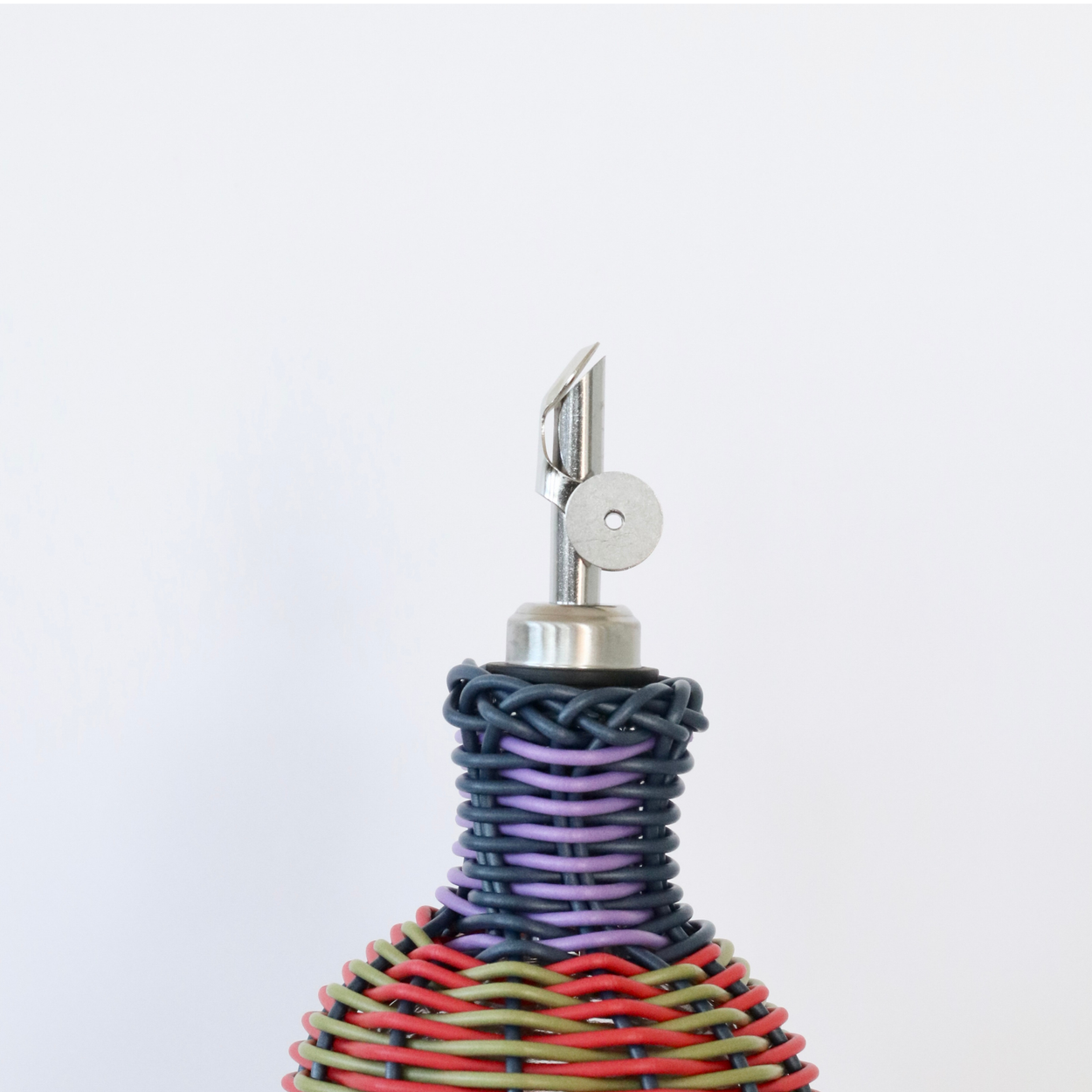 Decorative bottle with woven design and metallic nozzle on a white background