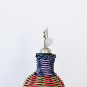 Decorative bottle with woven design and metallic nozzle on a white background
