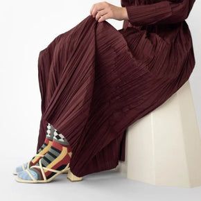 Person wearing a burgundy pleated dress with colorful Bonne Maison socks on a white background