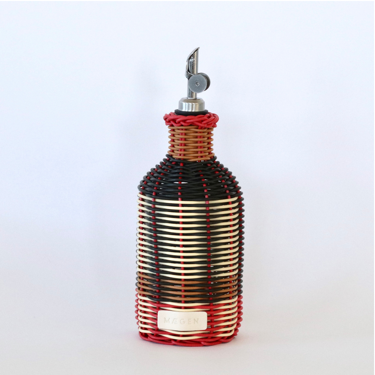 Decorative olive oil bottle with black, red and cream woven design and metallic nozzle on a white background.