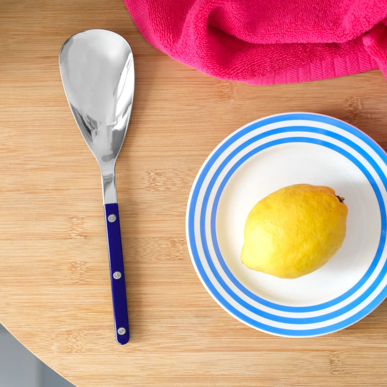 Sabre Bistrot Navy Rice Spoon on table with lemon on plate