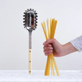 Womens hand holding pasta next to a ivory Sabre Paris Bistrot Spaghetti Server