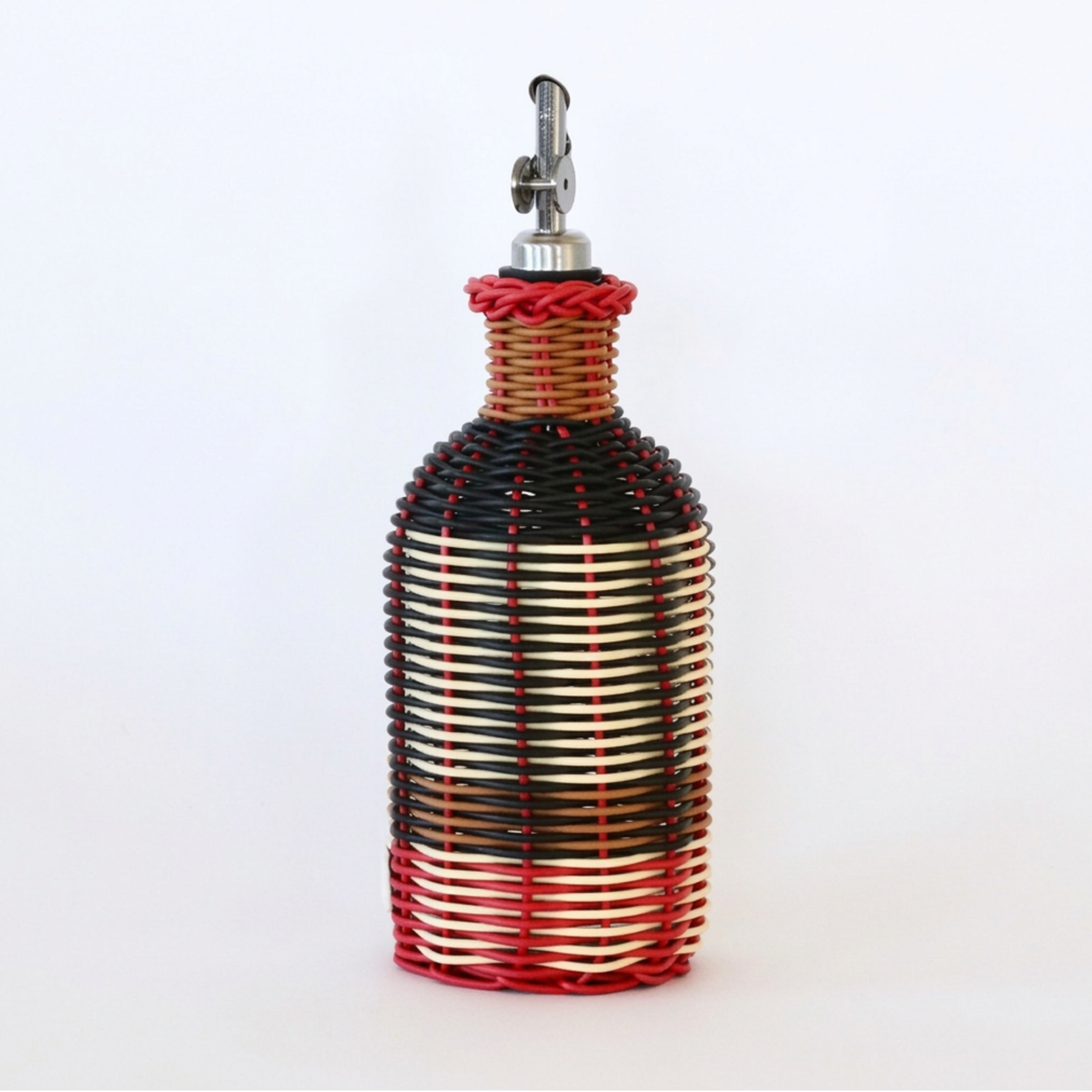 Decorative olive oil bottle with black, red and cream woven design and metallic nozzle on a white background