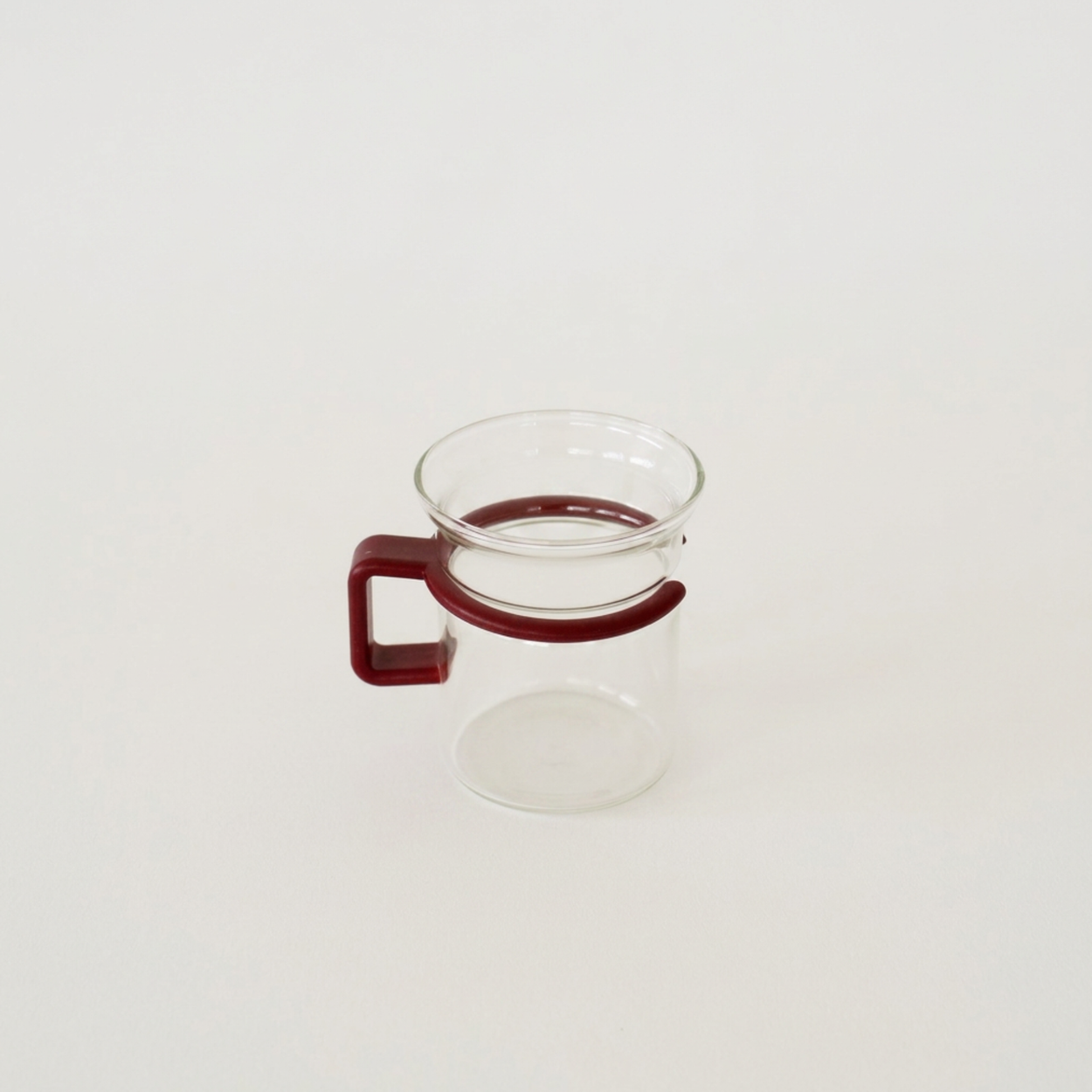 Clear glass mug with a red handle on a white background