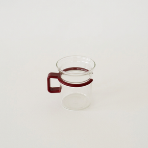 Clear glass mug with a red handle on a white background