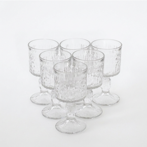 Six clear textured glass candleholders with pedestal bases, arranged in a cluster on a white background.