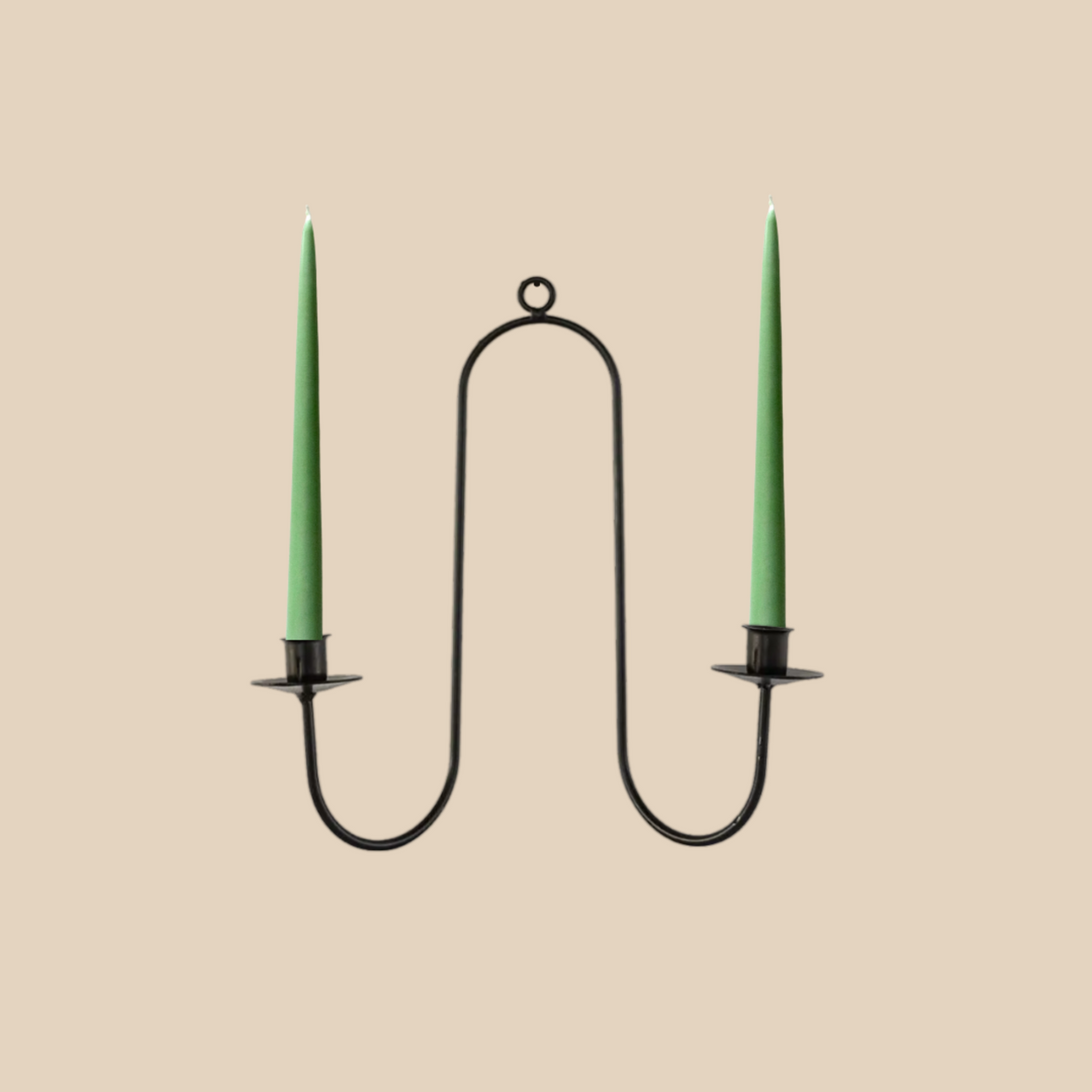Black metal candle holder with two green candles on a beige background