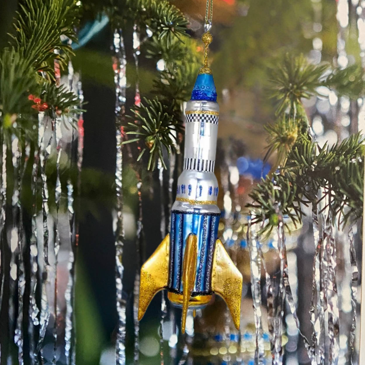 Decorative rocket ornament hanging on a Christmas tree.