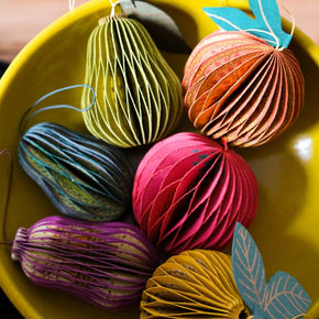 Colorful paper ornaments with leaf accents in a yellow bowl.