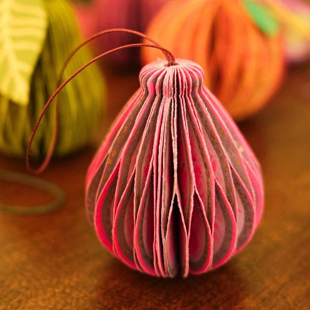 Colorful paper fig ornaments on a wooden surface with a blurred background