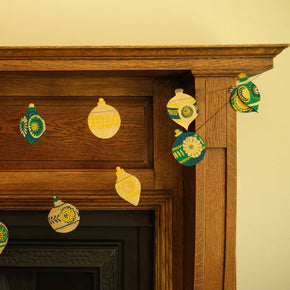 Decorative paper ornaments hanging on a wooden mantelpiece.