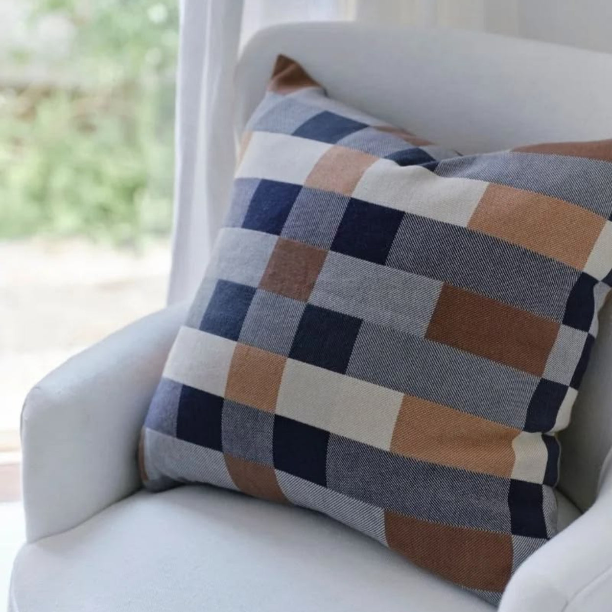 Mungo Seven Seas Checkered double cotton  pillow on a white chair with a blurred outdoor background