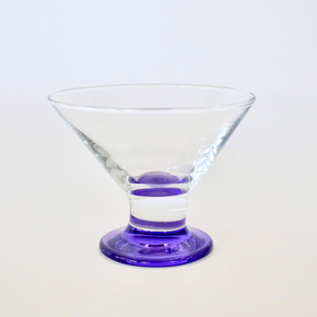 Clear glass martini glass with a purple base on a white background