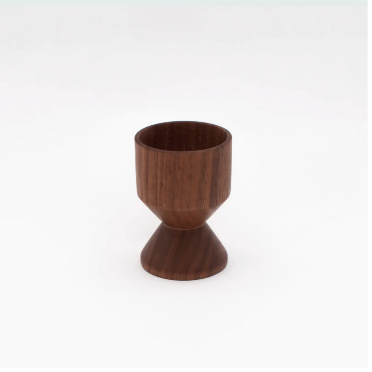 Turned wood eggcup against a white background.