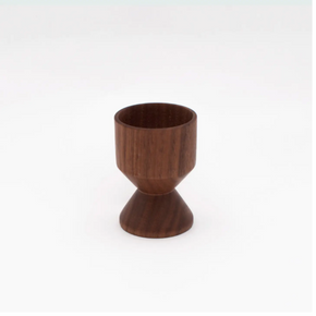 Turned wood eggcup against a white background.