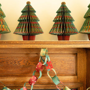 Decorative paper Christmas trees on a mantelpiece with a paper chain.