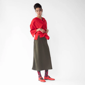 Woman with red shoes and khaki skirt wearing Bonne Maison Tiger socks against a white backdrop.
