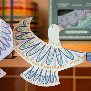 Decorative paper dove with colorful patterns on a wooden surface.
