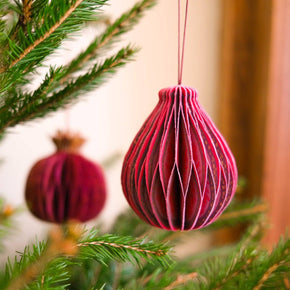 Pink decorative ornament hanging on a Christmas tree branch